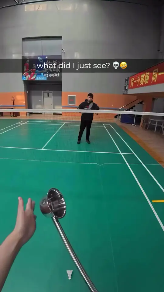 An oversized shuttlecock sails across a badminton court at a lone player
