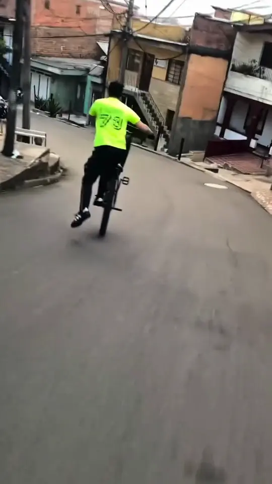 A cyclist pulls up the front wheel on a narrow hillside street